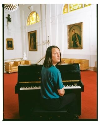 Thijs van Vuure zit achter de piano en kijkt over zijn schouder.