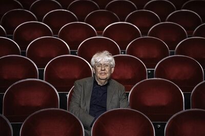 Beeld bij Geert Mak - een helder theatercollege over de huidige situatie in de wereld: een oudere man met wit haar, een bril en een grijs colbert zit alleen in een lege theaterzaal vol rode fluwelen stoelen en kijkt in de camera.