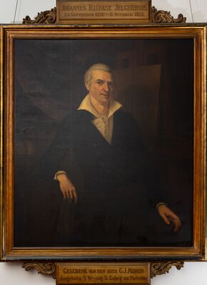 Geschilderd portret van een man met wit haar, in een zwarte jas met een hoge witte kraag en jabot, achter hem een schildersezel. Op het plaatje boven de lijst: Johannes Rienksz. Jelgerhuis, 24 September 1770 – 6 October 1836; eronder: Geschenk van den heer C.J. Morin.