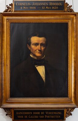 Donker geschilderd portret van een man met donker golvend haar in een zwarte jas, wit overhemd en zwarte strik, tegen een bijna zwarte achtergrond. In een vergulde lijst; boven het schilderij een plaatje met CORNELIS JOHANNES ROOBOL 4 Mei 1806 — 12 Mei 1870, eronder: Aangeboden door de Vereeniging voor de Galerij van Portretten.