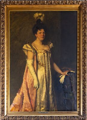 Geschilderd portret ten voeten uit van een vrouw in een lichte empirejapon met lange witte handschoenen, een roze sleep en veren in het opgestoken haar; haar hand rust op een stoelleuning. Linksboven gesigneerd: Th. Schwartze, 1901. Op het plaatje onderaan de lijst: Mevr. Sophie Pauwels van Biene.