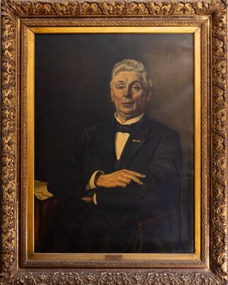 Geschilderd portret van een oudere man met wit haar, in rok met een wit overhemd, een zwarte strik en twee lintjes op de revers; zijn armen rusten over elkaar. Op het plaatje onderaan de lijst: W.P. de Leur, regisseur.
