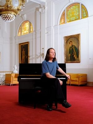 Thijs van Vuure zit op een pianokrukje voor een piano