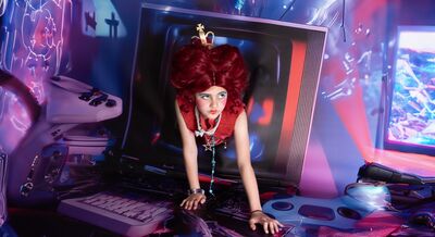 Campagnebeeld voor Alice in Wonderland: een meisje met een hoge rode pruik en een gouden kroontje kruipt door het lege scherm van een oude televisie naar voren, tussen stapels beeldschermen, toetsenborden en gameconsoles in roze en blauw licht.