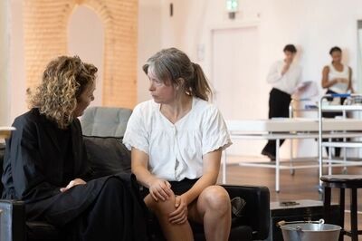 Twee vrouwen kijken elkaar aan terwijl ze op een bank zitten.