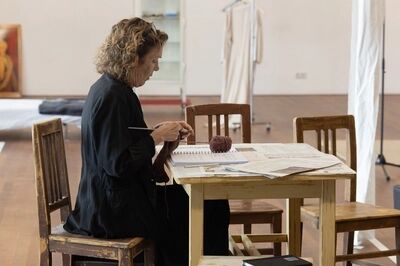 Een vrouw zit te breien aan tafel.