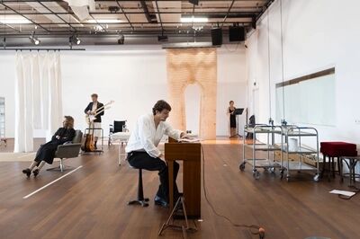 Een man zit te schrijven achter een piano.