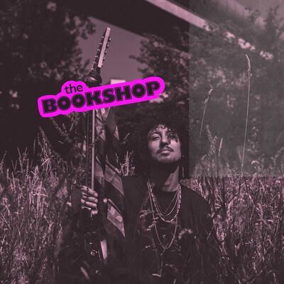 Beeld bij Nosebleed Blues: een paars getinte foto van een muzikant met krullend haar die een gitaar rechtop naast zich houdt, staand in hoog gras. Linksboven staat het roze logo 'the BOOKSHOP'.
