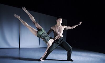 Twee dansers in Blast a universe op een donker toneel: een danser met ontbloot bovenlijf staat wijdbeens en houdt een danseres vast die horizontaal voorover in zijn armen ligt, met gestrekte benen omhoog.