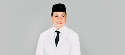 Campagnebeeld voor Soekarno: een speler in een wit colbert met wit overhemd, zwarte stropdas en zwarte peci kijkt glimlachend in de camera, voor een lichtgrijze achtergrond.